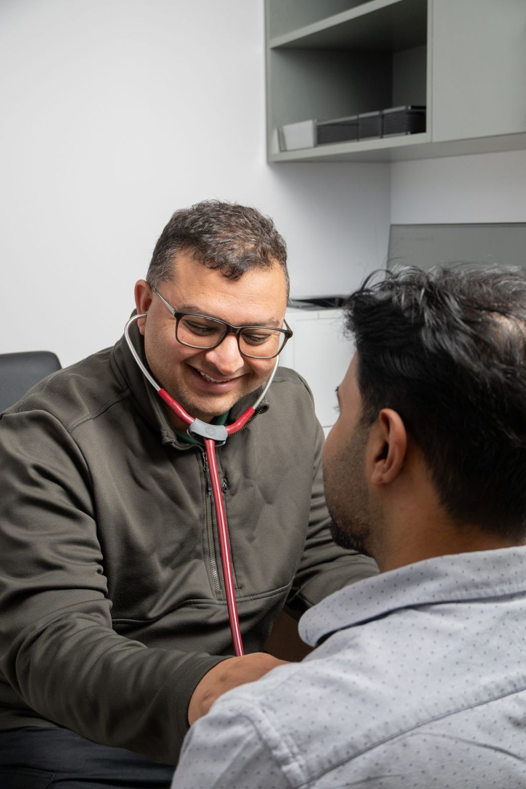 Dr Mujtaba Ali listening to a patient's chest with a stethoscope