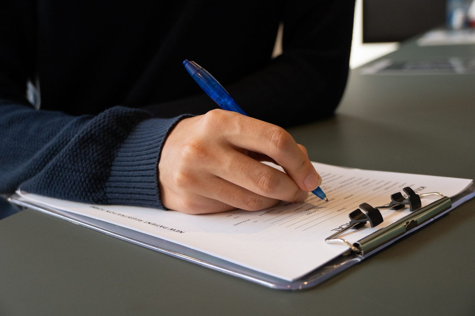 A patient filling in a Kilmore Village Medical registration form on a clipboard