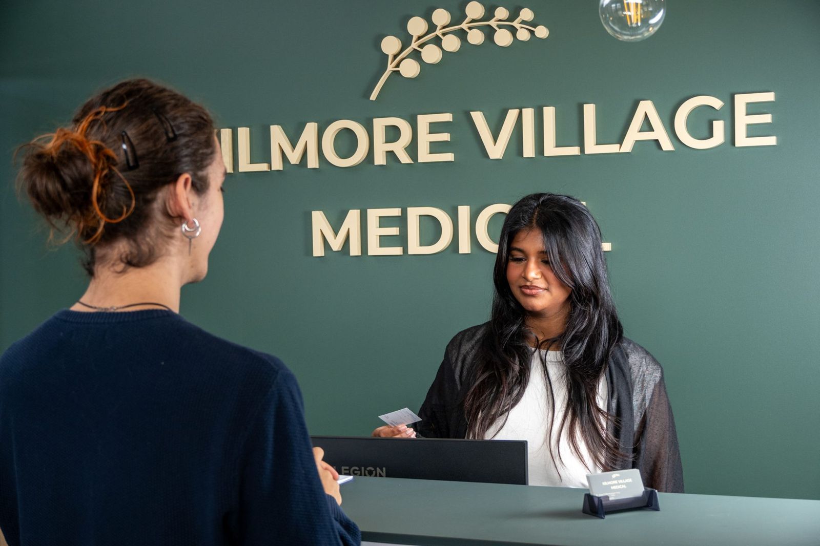 A member of our reception team smiling as she helps a patient at the front desk