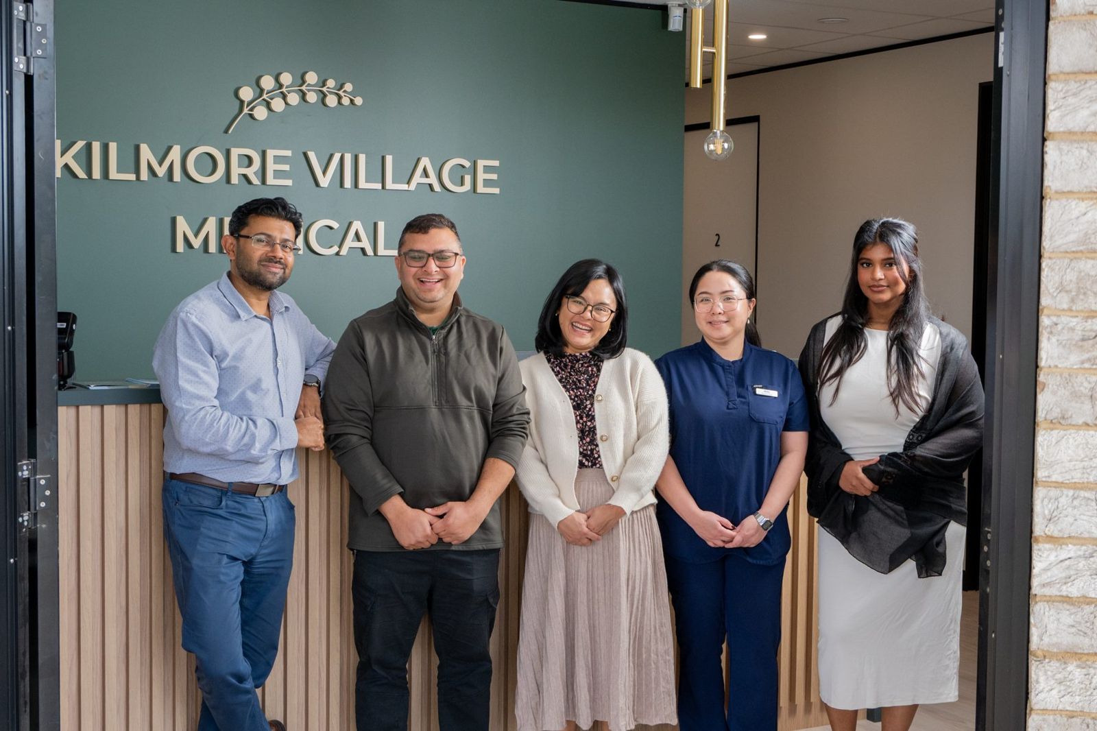 Our doctors, nurse and front desk team in front of the Kilmore Village Medical sign